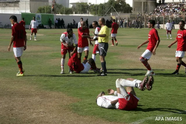 A Palestinian football player falls on the ground during a football match between Khan Yunis Youth club (red shirt) and Rafah Collective club (white shirt) on Jun 27, 2011 in the southern Gaza Strip town of Rafah. Photo...
