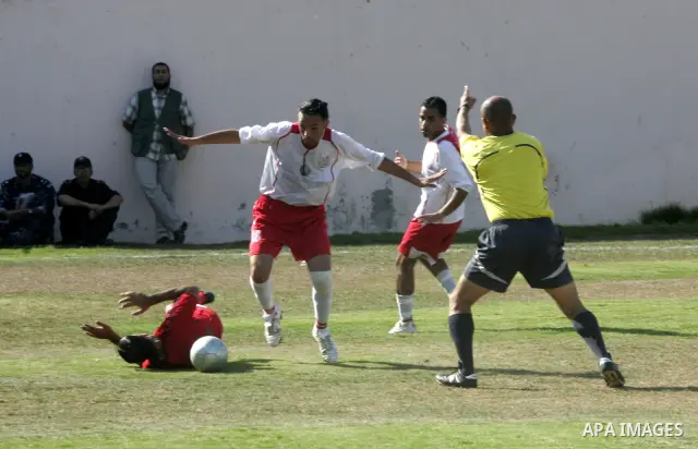 Palestinian football players challenge for the ball during a football match between Khan Yunis Youth club (red shirt) and Rafah Collective club (white shirt) on Jun 27, 2011 in the southern Gaza Strip town of Rafah. Phot...