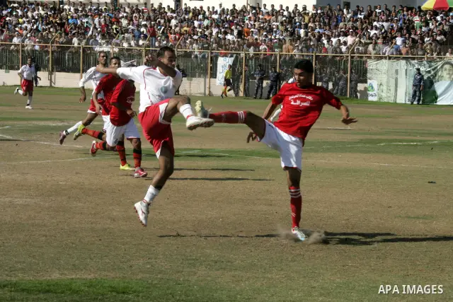 Palestinian football players challenge for the ball during a football match between Khan Yunis Youth club (red shirt) and Rafah Collective club (white shirt) on Jun 27, 2011 in the southern Gaza Strip town of Rafah. Phot...