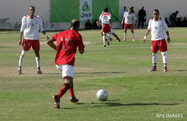 Palestinian football players challenge for the ball during a football match between Khan Yunis Youth club (red shirt) and Rafah Collective club (white shirt) on Jun 27, 2011 in the southern Gaza Strip town of Rafah. Phot...