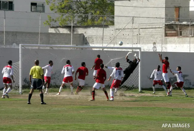 Palestinian football players challenge for the ball during a football match between Khan Yunis Youth club (red shirt) and Rafah Collective club (white shirt) on Jun 27, 2011 in the southern Gaza Strip town of Rafah. Phot...