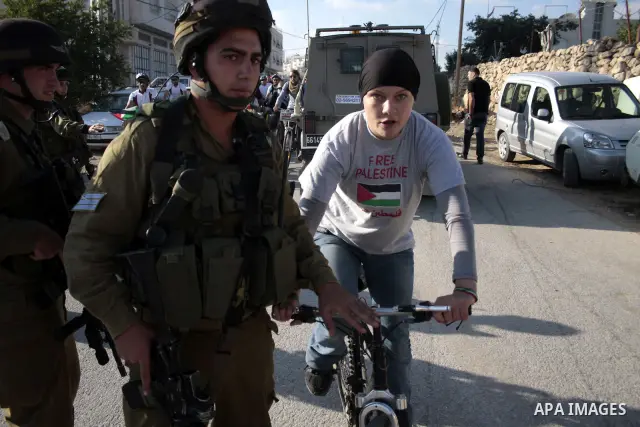 Palestinian and foreign bikers wait behind a cordon of Israeli security forces to ride their bicycles under the slogan of "biking without borders" across a Palestinian road closed off by Israeli troops to be used by Jewi...