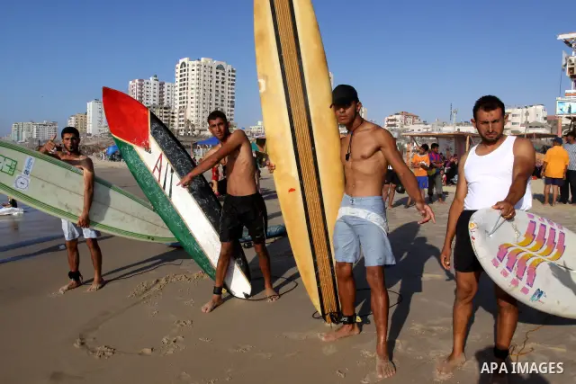 Palestinian youths carry their boards as they prepare to surf in Gaza City on Jun 28,2011. Photo by Mohammed Asad