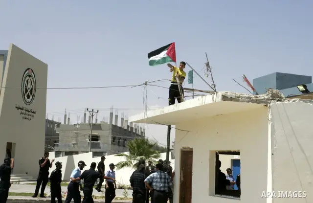 A Palestinian boy raises the national flag on the police building while the Palestinian Prime Minister in Gaza strip, Ismail Haniya opens the headquarters of the new Palestinian police, which was rebuilt after destroyed...