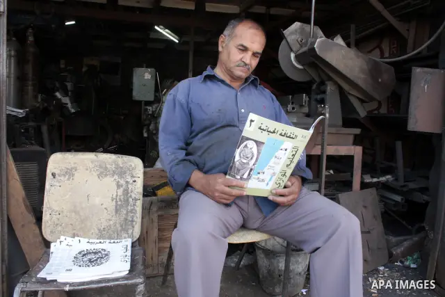 A Palestinian elderly man Elias Abdel-Hay reads a book at his shop as he prepares to study in the high school "Twajihi" after he left studing for 47 years old in the West Bank city of Hebron on June 29, 2011. Where he co...