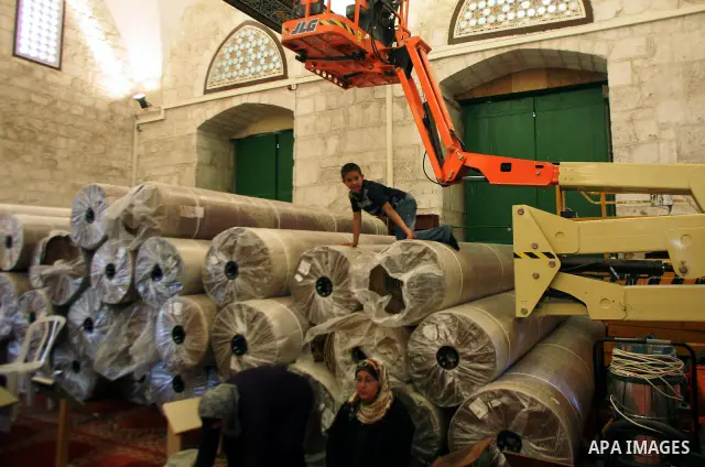Palestinians stand inside the Al-Aqsa Mosque in Jerrusalem's old city on June 29, 2011 near rolls of new carpet that will be fitted inside the mosque. According to Sheikh Azzam Khatib, the head of the Islamic Waqf in Jer...