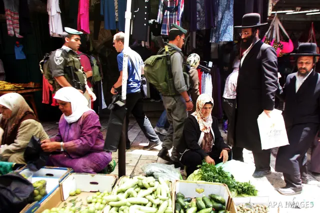 Ultra orthodox Jewish men walk past Palestinian vendors at the main market in Jerrusalem's old city on June 29, 2011. According to Sheikh Azzam Khatib, the head of the Islamic Waqf in Jerusalem, work have started to fit...
