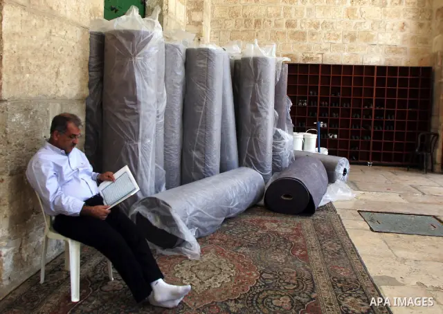 A Palestinian man sits inside the Al-Aqsa Mosque in Jerrusalem's old city on June 29, 2011 near rolls of new carpet that will be fitted inside the mosque. According to Sheikh Azzam Khatib, the head of the Islamic Waqf in...