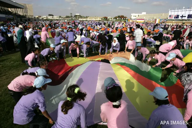 Palestinian children perform with coloured parachutes during summer camp activities supervised by the UN Relief and Works Agency (UNRWA) in Khan Yunis in the southern Gaza Strip on June 30, 2011. Photo by Abed Rahim Khat...
