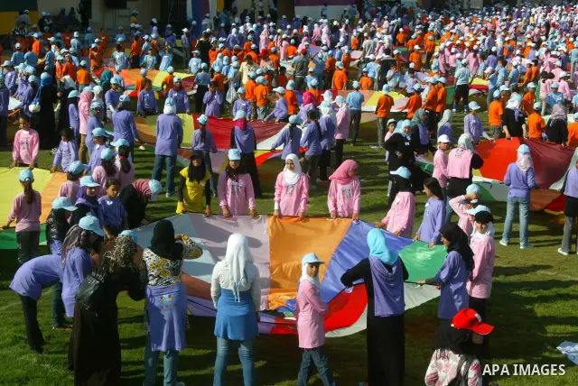 Palestinian children perform with coloured parachutes during summer camp activities supervised by the UN Relief and Works Agency (UNRWA) in Khan Yunis in the southern Gaza Strip on June 30, 2011. Photo by Abed Rahim Khat...