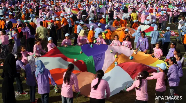 Palestinian children perform with coloured parachutes during summer camp activities supervised by the UN Relief and Works Agency (UNRWA) in Khan Yunis in the southern Gaza Strip on June 30, 2011. Photo by Ali Jadallah