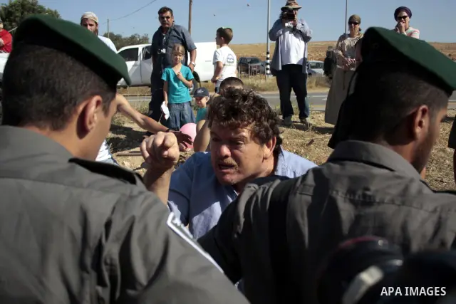 Israeli soldiers and an Israeli settler argue as security forces evacuate a group of Jewish settlers who tried to make a sit-in on a Palestinian land that was being cultivated by Palestinian farmers, on July 1, 2011 in t...