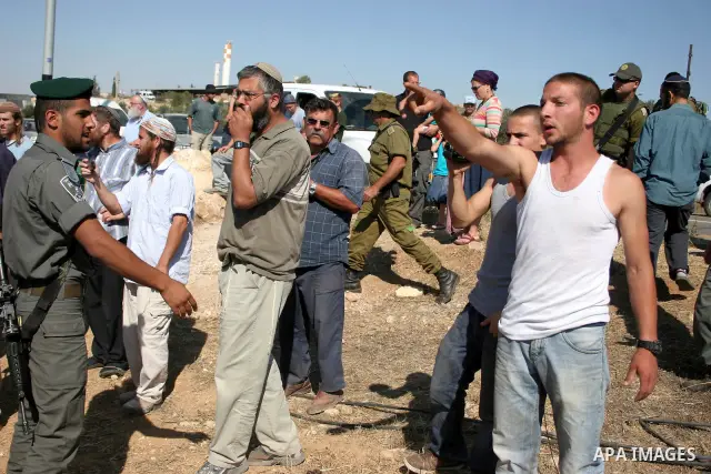 Israeli soldiers and an Israeli settler argue as security forces evacuate a group of Jewish settlers who tried to make a sit-in on a Palestinian land that was being cultivated by Palestinian farmers, on July 1, 2011 in t...