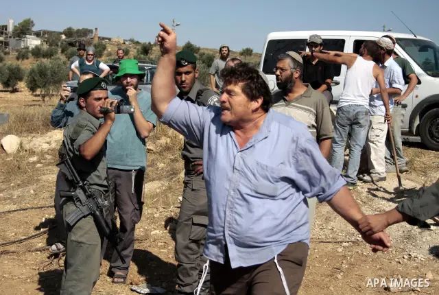 Israeli soldiers and an Israeli settler argue as security forces evacuate a group of Jewish settlers who tried to make a sit-in on a Palestinian land that was being cultivated by Palestinian farmers, on July 1, 2011 in t...