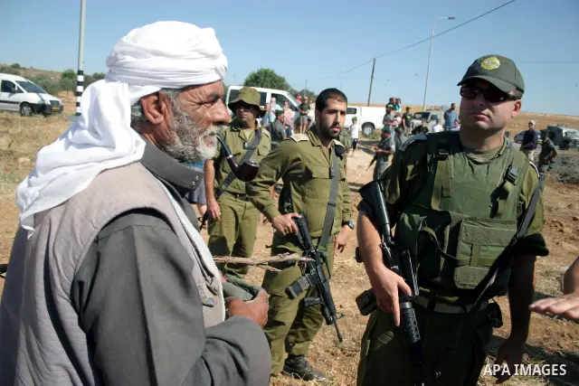 Palestinian farmers work at their land as Israeli border guards prepare to evacuate Jewish settlers who tried to make a sit-in on a Palestinian land that was being cultivated by farmers, on July 1, 2011, in the West Bank...