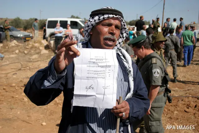 Palestinian farmers work at their land as Israeli border guards prepare to evacuate Jewish settlers who tried to make a sit-in on a Palestinian land that was being cultivated by farmers, on July 1, 2011, in the West Bank...
