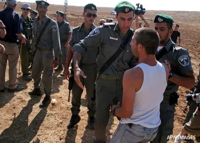 Israeli soldiers and an Israeli settler argue as security forces evacuate a group of Jewish settlers who tried to make a sit-in on a Palestinian land that was being cultivated by Palestinian farmers, on July 1, 2011 in t...