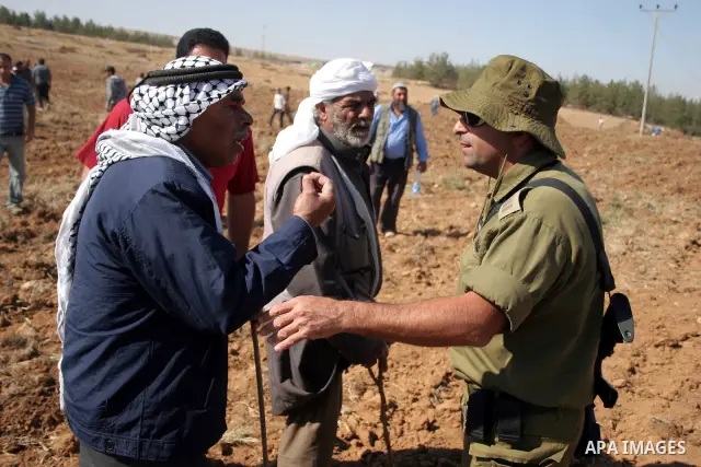 Palestinian farmers work at their land as Israeli border guards prepare to evacuate Jewish settlers who tried to make a sit-in on a Palestinian land that was being cultivated by farmers, on July 1, 2011, in the West Bank...