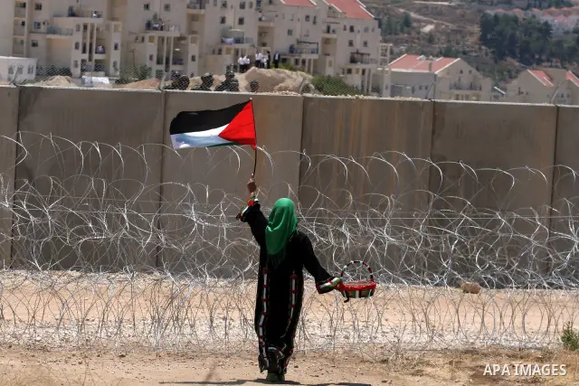 A Palestinian woman celebrates at the site where Israeli forces ripped down part of its controversial separation barrier outside the West Bank village of Bilin, the focus of anti-barrier protests, on July 1, 2011. Israel...