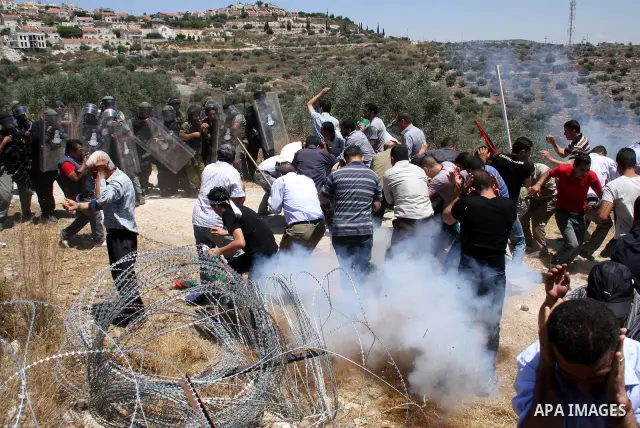 Palestinian villagers run for cover from tear gas fired by Israeli forces during clashes follo wing a protest against the closure of a road during the second Intifada by Jewish settlers from the nearby settlement of Kadu...