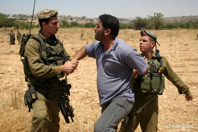 An Israeli soldier detains a protester during a demonstration by Palestinian, Israeli and foreign activists against the demolishing of farm land to be used in the construction of Jewish settlements near the existing Isra...