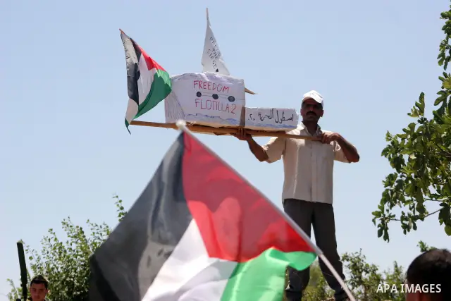 Israeli soldiers stand guard as Palestinian, Israeli and foreign activists hold a mock for the Gaza-bound international Freedom Flotilla during a demonstration against the demolishing of farm land to be used in the const...