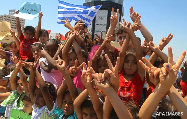 Palestinian children wave a Greek flag during a rally in Gaza City in support of the international Freedom Flotilla hoping to breach Israel's sea blockade on Gaza as it remained banned by Greece from setting sail on July...