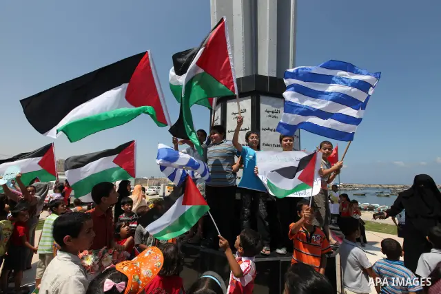 Palestinian children wave Palestinian and Greek flags during a rally in Gaza City in support of the international Freedom Flotilla hoping to breach Israel's sea blockade on Gaza as it remained banned by Greece from setti...