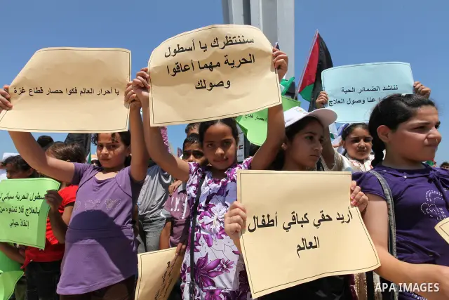 Palestinian children wave Palestinian flags and banners during a rally in Gaza City in support of the international Freedom Flotilla hoping to breach Israel's sea blockade on Gaza as it remained banned by Greece from set...