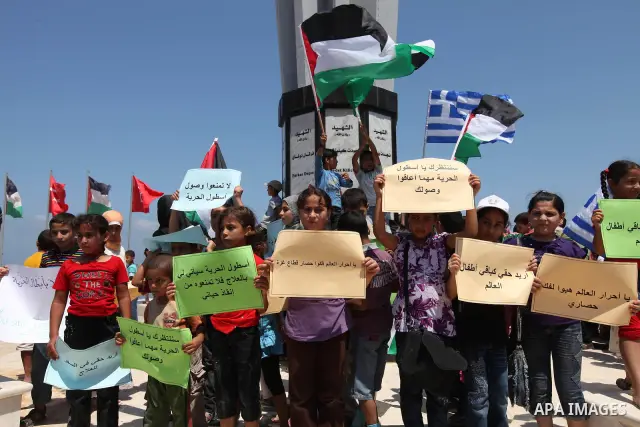 Palestinian children wave Palestinian and Greek flags during a rally in Gaza City in support of the international Freedom Flotilla hoping to breach Israel's sea blockade on Gaza as it remained banned by Greece from setti...