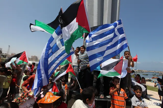 Palestinian children wave Palestinian and Greek flags during a rally in Gaza City in support of the international Freedom Flotilla hoping to breach Israel's sea blockade on Gaza as it remained banned by Greece from setti...