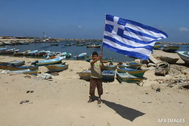 A Palestinian boy waves a Greek flag during a rally in Gaza City in support of the international Freedom Flotilla hoping to breach Israel's sea blockade on Gaza as it remained banned by Greece from setting sail on July 3...
