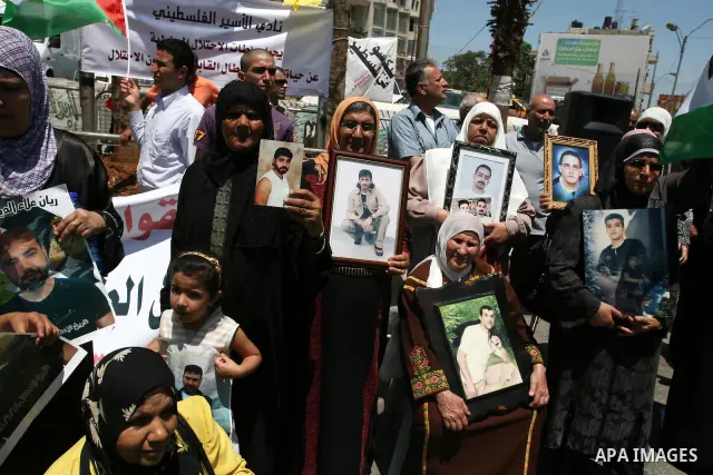 Palestinians hold pictures of their relatives held in Israeli jails during a protest calling for their release in the West Bank city of Ramallah on July 3, 2011. Israel currently holds about 5,600 Palestinian prisoners i...