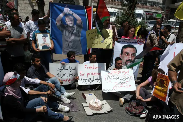 Palestinians hold pictures of their relatives held in Israeli jails during a protest calling for their release in the West Bank city of Ramallah on July 3, 2011. Israel currently holds about 5,600 Palestinian prisoners i...