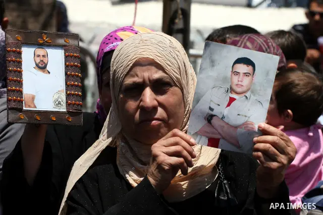 A Palestinian woman holds pictures of her relative held in Israeli jails during a protest calling for their release in the West Bank city of Ramallah on July 3, 2011. Israel currently holds about 5,600 Palestinian prison...