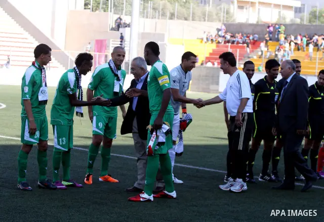 Palestinian Prime Minister Salam Fayyad shakes hand with Palestinian players during a soccer match between the Palestinian and Afghanistan national teams in the West bank city of Ramallah, Sunday July 3, 2011. The Palest...