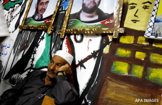 Relatives of Palestinian prisoners hold their pictures as they prepare to sleep at Gaza City's Red Cross offices on July 3,2011, during a protest calling for the release of Palestinian prisoners from Israeli jails. Photo...