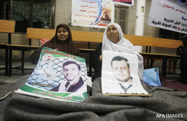 Relatives of Palestinian prisoners hold their pictures as they prepare to sleep at Gaza City's Red Cross offices on July 3,2011, during a protest calling for the release of Palestinian prisoners from Israeli jails. Photo...
