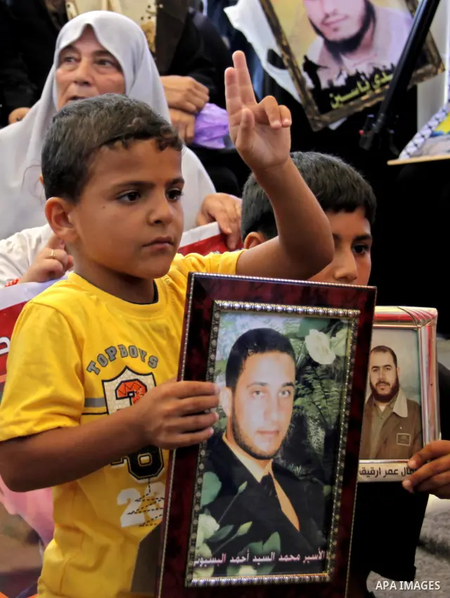 A Palestinian boy holds picture of his relative held in Israeli jails during a protest calling for their release in front of the Red Cross in Gaza city on July 4, 2011. Israel currently holds about 5,600 Palestinian pris...