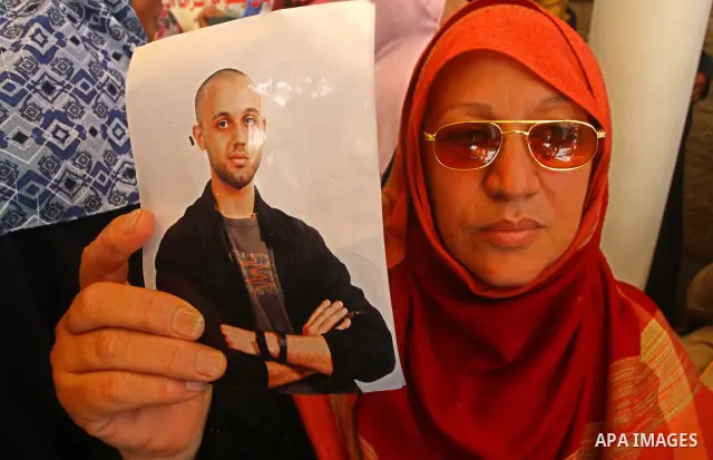 A Palestinian woman holds picture of her relative held in Israeli jails during a protest calling for their release in front of the Red Cross in Gaza city on July 4, 2011. Israel currently holds about 5,600 Palestinian pr...