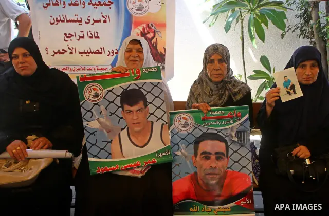 Palestinians hold pictures of their relatives held in Israeli jails during a protest calling for their release in front of the Red Cross in Gaza city on July 4, 2011. Israel currently holds about 5,600 Palestinian prison...
