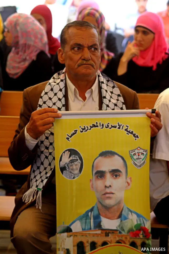A Palestinian man holds picture of his relative held in Israeli jails during a protest calling for their release in front of the Red Cross in Gaza city on July 4, 2011. Israel currently holds about 5,600 Palestinian pris...