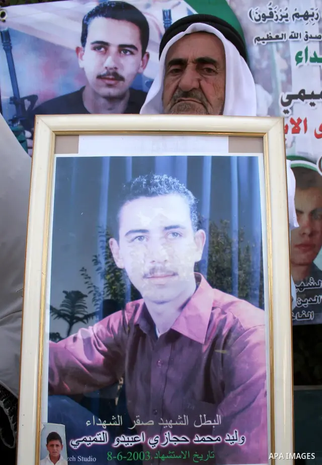 Palestinian relatives of Waleed Abedo hold his picture on July 4, 2011, in the West Bank town of Hebron, after Palestinian minister for civil affairs Hussein al-Sheikh announced that Israel is to release the bodies of 84...