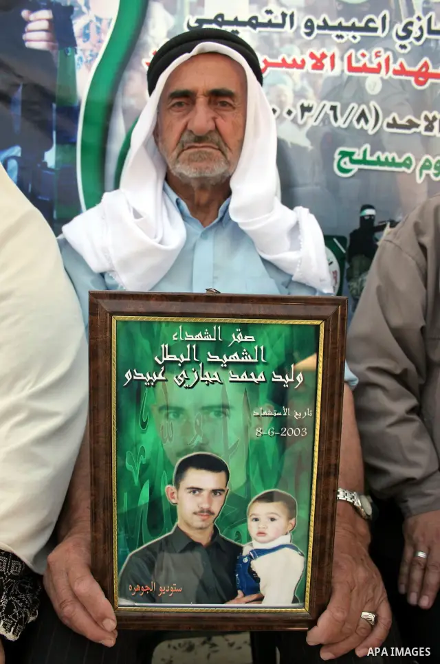 Palestinian relatives of Waleed Abedo hold his picture on July 4, 2011, in the West Bank town of Hebron, after Palestinian minister for civil affairs Hussein al-Sheikh announced that Israel is to release the bodies of 84...