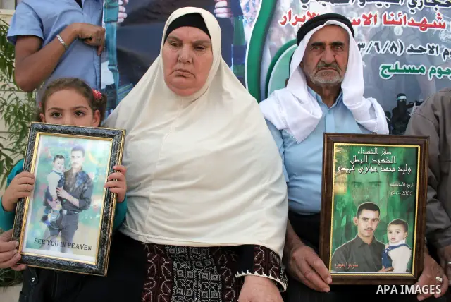 Palestinian relatives of Waleed Abedo hold his picture on July 4, 2011, in the West Bank town of Hebron, after Palestinian minister for civil affairs Hussein al-Sheikh announced that Israel is to release the bodies of 84...