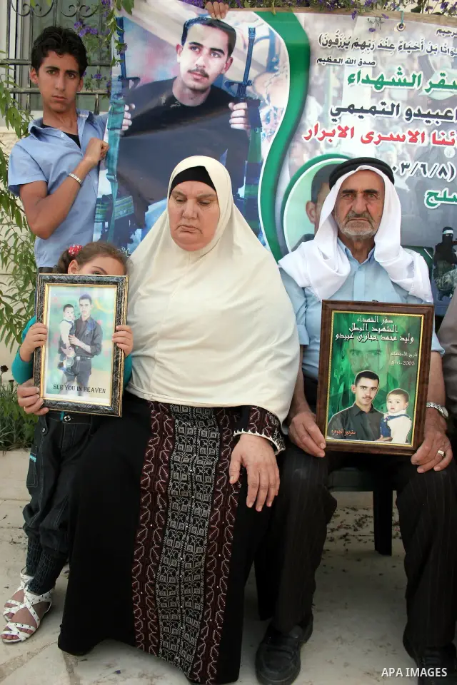 Palestinian relatives of Waleed Abedo hold his picture on July 4, 2011, in the West Bank town of Hebron, after Palestinian minister for civil affairs Hussein al-Sheikh announced that Israel is to release the bodies of 84...