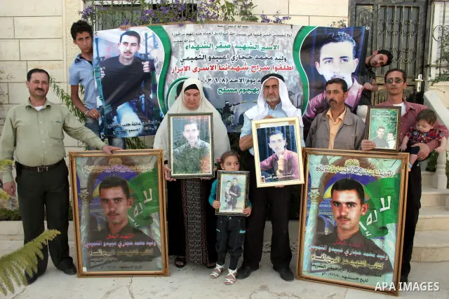 Palestinian relatives of Waleed Abedo hold his picture on July 4, 2011, in the West Bank town of Hebron, after Palestinian minister for civil affairs Hussein al-Sheikh announced that Israel is to release the bodies of 84...