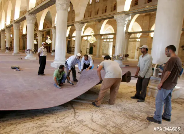 Palestinians fit rolls of new carpet inside the Al-Aqsa Mosque in Jerusalem's Old City on July 4, 2011. According to Sheikh Azzam Khatib, the head of the Islamic Waqf in Jerusalem, work have started to fit 5000 square me...