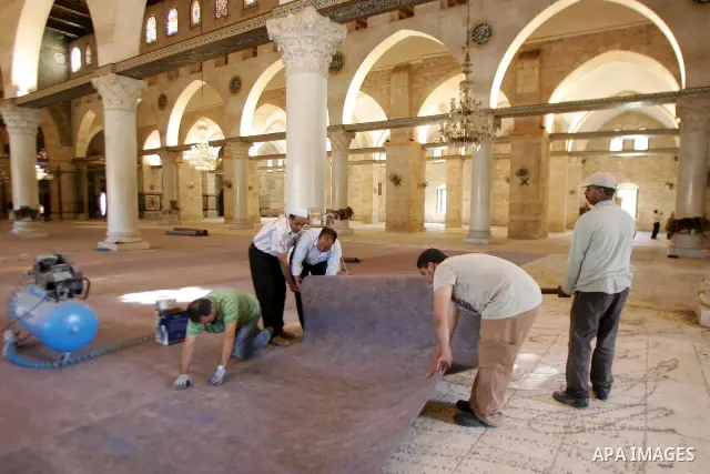Palestinians fit rolls of new carpet inside the Al-Aqsa Mosque in Jerusalem's Old City on July 4, 2011. According to Sheikh Azzam Khatib, the head of the Islamic Waqf in Jerusalem, work have started to fit 5000 square me...