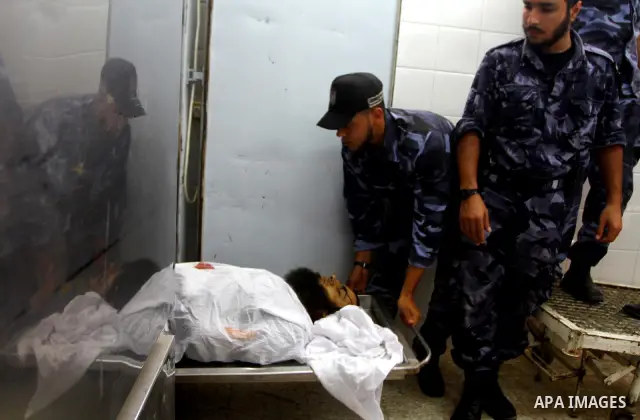 Hamas security officers stand next to bodies of two Palestinians killed by Israeli forces, at the morgue of Al-Aqsa hospital in Deir Al Balah, central Gaza Strip, Tuesday, July 5, 2011. An Israeli attack struck a target...